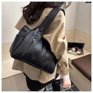 Close-up of black tote bag with litchi texture and side zipper detail on a shoulder