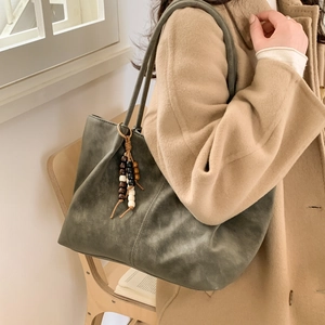 Vintage dark green suede tote bag with beaded tassel shown on a beige wool coat