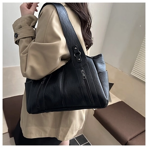 Side view of black large capacity tote bag featuring multi-zipper pockets and lychee texture