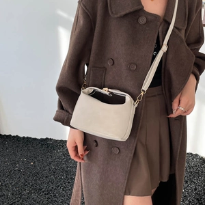 Chic beige leather crossbody bag with adjustable strap and unique folding closure