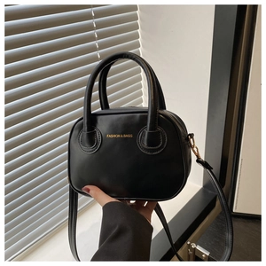 Gros plan d'un petit sac bandoulière noir avec lettrage doré et doubles anses
