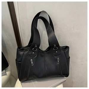 Detail of black pebbled leather tote bag featuring silver studs and double zipper pockets