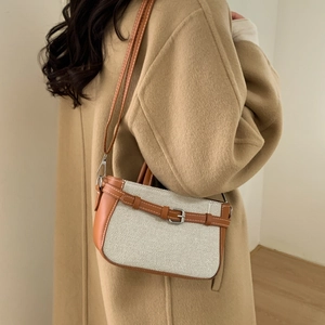 Sac seau rétro en toile et cuir marron porté avec un manteau en laine couleur chameau