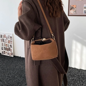Retro dark brown crossbody pillow bag with metal lock shown on a model in wool coat