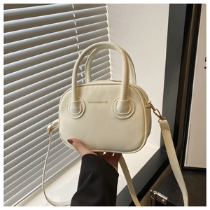 Détail du mini sac à main crème avec texte doré et bandoulière réglable pratique