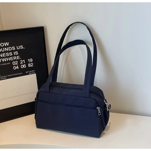 Detail of navy blue nylon tote bag with dual shoulder straps and metallic zippers