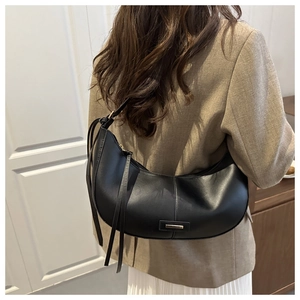 Détail d'un sac hobo en cuir mat noir avec des lignes douces et un ornement métallique