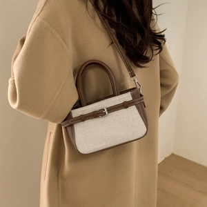 Sac seau tendance en toile et cuir avec poignée et bandoulière porté par un mannequin
