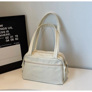 Detailed view of cream-white canvas tote bag featuring double straps and large front zip pocket