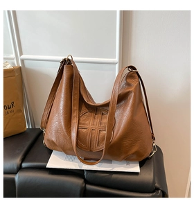 Detail of brown pebbled leather hobo bag with circular logo and golden hardware