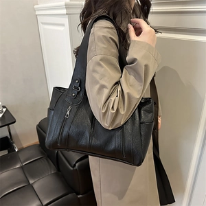 Large black pebbled faux leather tote bag with shoulder straps worn by model