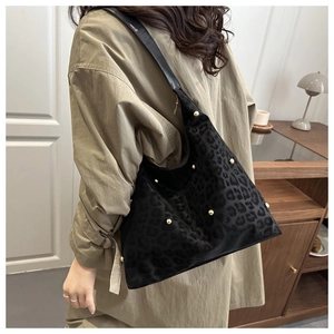 Dettaglio di una borsa shopper leopardata con borchie dorate e morbida pelle scamosciata