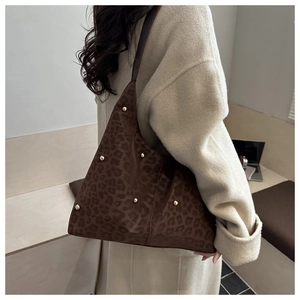Modella che indossa una grande borsa tote leopardata con borchie dorate e tracolla
