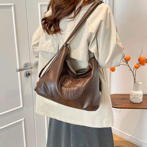 Retro large brown hobo tote bag in soft leather shown on shoulder in cozy indoor setting