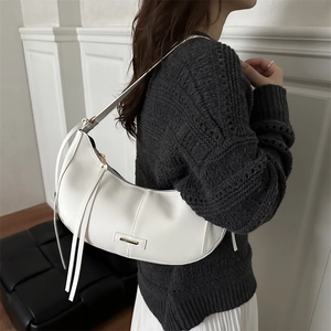Minimalist white leather crescent crossbody bag with long tassel details on model