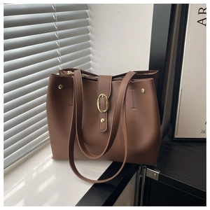 Detail view of large brown faux leather tote bag with gold buckle and slim straps