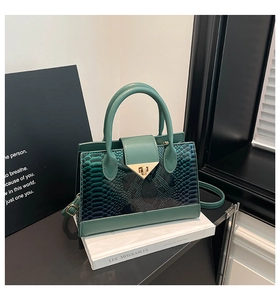 Close-up of mint green handbag featuring faux snakeskin texture and golden triangle lock