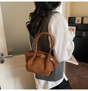 Detail of caramel suede handbag showing a decorative buckle and matte textured surface