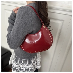 Detail of red crescent moon bag with golden rivets and patent leather finish