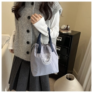 Détail du sac cabas étanche en nylon avec cordon de serrage et logo ours mignon