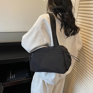 Minimalist black tote bag shown on model with drawstring detail in modern lifestyle setting