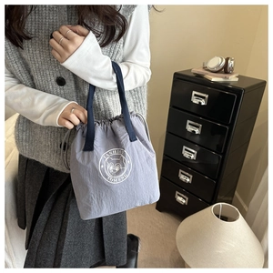 Détail du sac seau à cordon avec logo d'ours et poignées tissées bleu marine