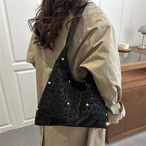 Borsa a mezzaluna nera con stampa leopardata e borchie dorate indossata a spalla