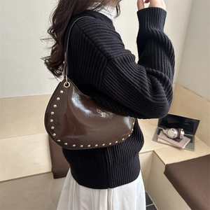 Fashionable dark brown crescent shoulder bag with metallic rivets in a casual lifestyle setting