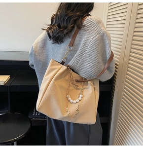 Detail of large tote bag with elegant pearl chain and metallic flower charms