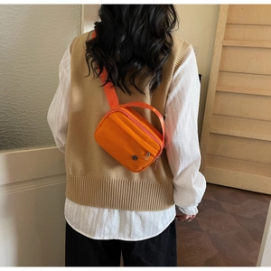 Détail du sac bandoulière orange vif montrant la sangle réglable sur un mannequin