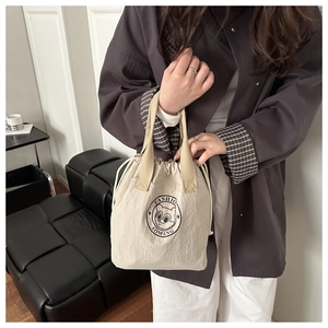 Détail du sac cabas beige à cordon avec logo dessin animé et poignées tressées