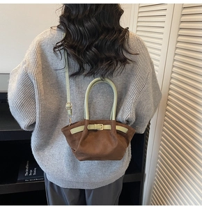 Detail of vintage matte brown tote bag with contrast green handle and decorative buckle