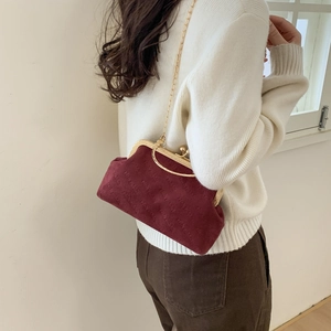 Burgundy velvet crossbody bag with gold chain and embossed texture worn by a model