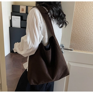 Detail view of large dark brown hobo shoulder bag with canvas texture on model