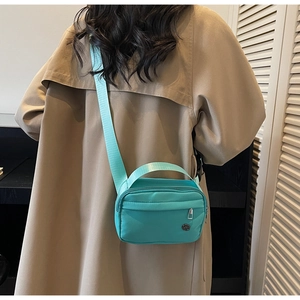 Vue arrière d'un mannequin portant un sac bandoulière en nylon vert menthe sur un manteau