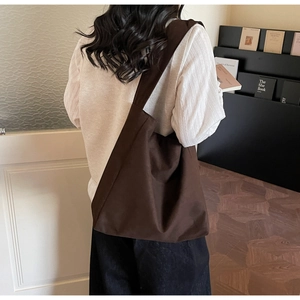 Minimalist deep coffee canvas tote bag shown in a lifestyle scene over a model's shoulder