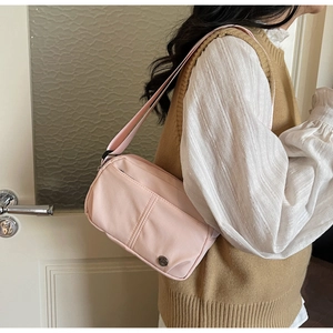 Detailed view of light pink nylon crossbody bag with metal logo and wide shoulder strap