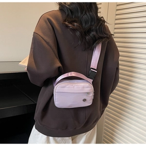 Gros plan d'un sac bandoulière en nylon violet avec sangle réglable sur un modèle