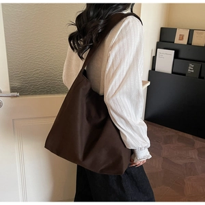 Vista laterale della borsa tote oversize in pelle scamosciata marrone scuro su modella
