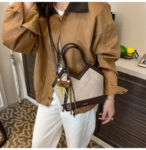 Close-up of quilted beige fabric bucket bag with brown leather trim and bear pendant