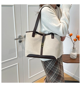 Detail of vintage canvas tote with brown leather trim and golden twist lock on shoulder