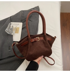 Detail of retro dark brown suede handbag with decorative leather strap and gold buckle