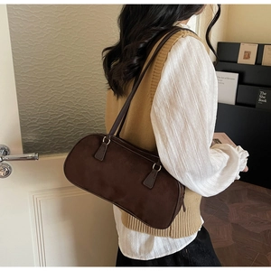 Detail of a dark brown suede shoulder bag with dual slim straps and golden buckles
