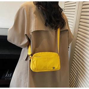 Detailed back view of a vibrant yellow nylon crossbody bag with a front zipper pocket