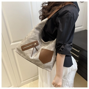Detail of grey canvas tote bag with brown leather shoulder strap and decorative pockets