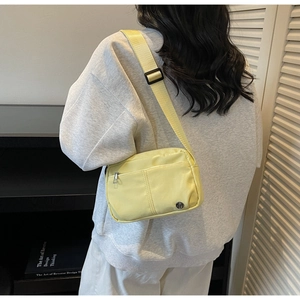Side view of light yellow nylon crossbody bag with adjustable wide strap on a model