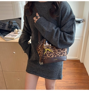 Detailed close-up of leopard print bucket bag with leather base and cute bear charm
