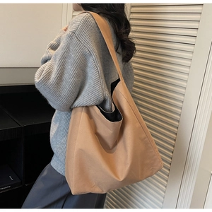 Detailed view of spacious khaki canvas tote bag with wide shoulder strap on model