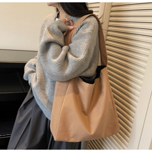 Close-up of a large caramel canvas tote bag with wide straps and natural fold details