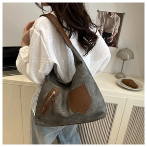 Detailed view of deep grey canvas tote bag featuring brown faux leather trim and tassel